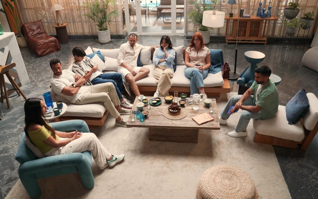 Seven Mountain View community members of different ages sit around a coffee table in a living room, listening to a speaker