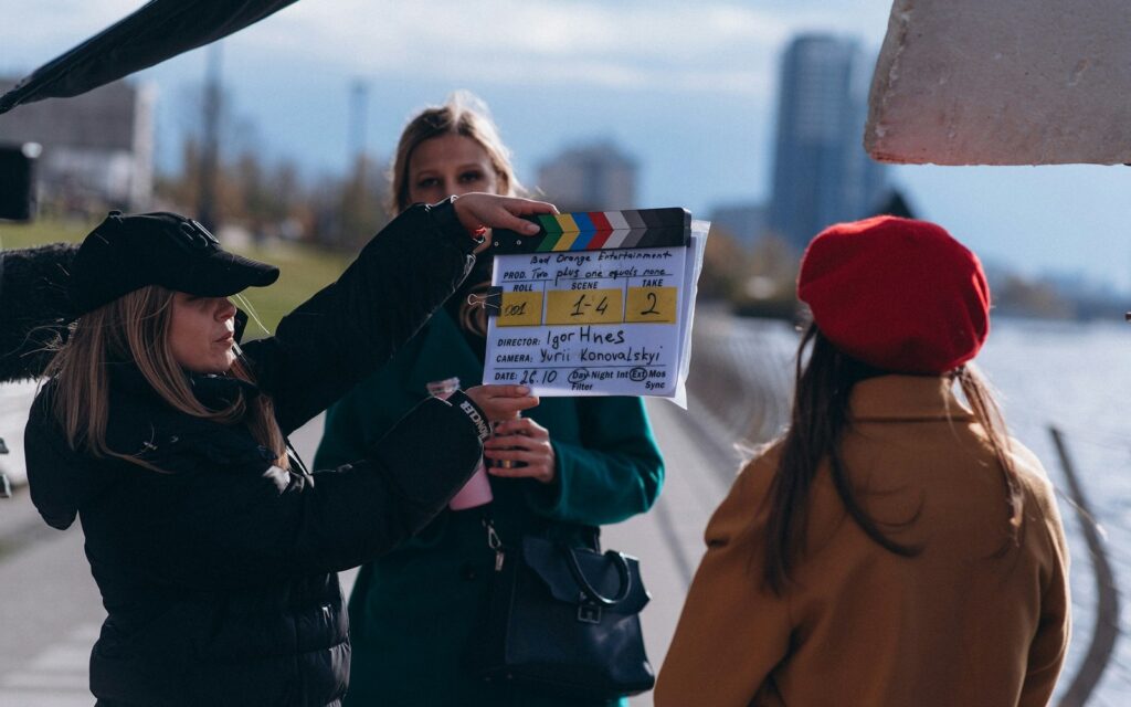 A film crew member holds up a clapperboard before a shot on an outdoor location